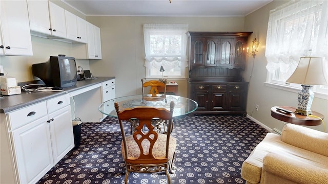 kitchen featuring white cabinetry, crown molding, baseboards, and carpet floors