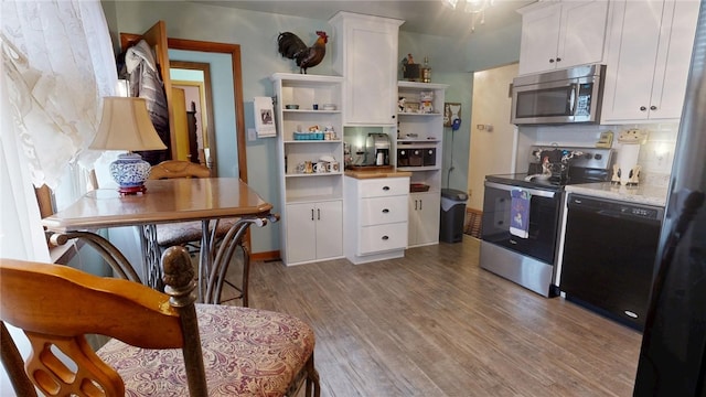 kitchen with open shelves, wood finished floors, white cabinetry, stainless steel appliances, and light countertops