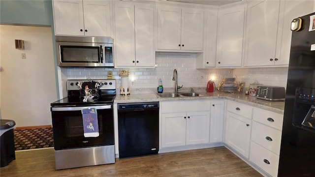 kitchen with wood finished floors, white cabinets, black appliances, and a sink