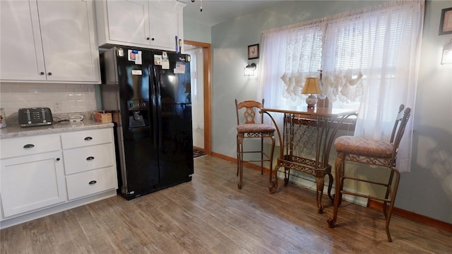 kitchen featuring black fridge with ice dispenser, white cabinetry, decorative backsplash, and wood finished floors