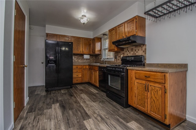 kitchen featuring black appliances, decorative backsplash, dark hardwood / wood-style flooring, and sink