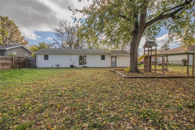 rear view of property with a yard and a playground