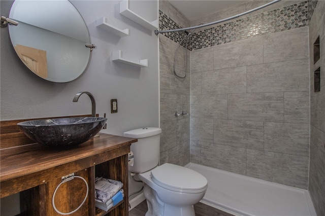 bathroom featuring hardwood / wood-style floors, toilet, a tile shower, and vanity