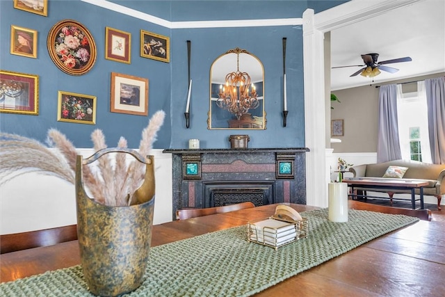 dining space with a fireplace, ceiling fan with notable chandelier, and wood finished floors
