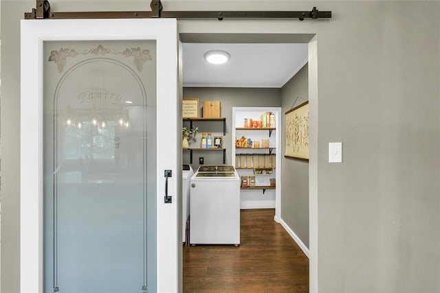 interior space featuring dark wood finished floors, a barn door, baseboards, ornamental molding, and washer and clothes dryer