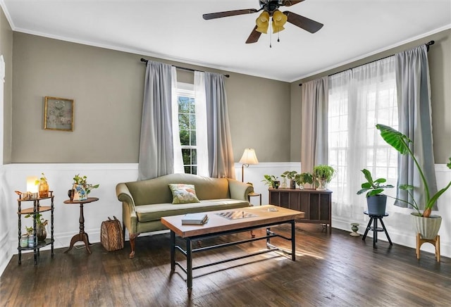 living area featuring wood finished floors, a ceiling fan, a wainscoted wall, and ornamental molding