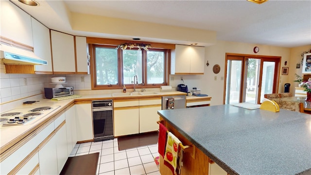 10 Lakeshore Ct, Danville, IL 61832 - kitchen featuring white electric cooktop, healthy amount of natural light, backsplash, and under cabinet range hood