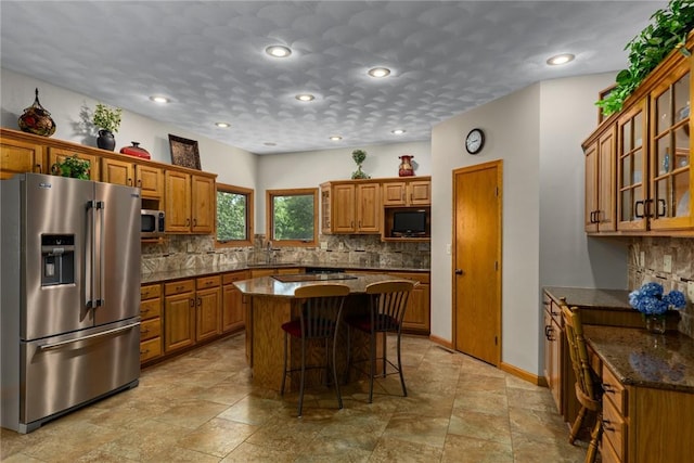 8434 Meadowview Rd, Effingham, IL 62401 - kitchen featuring appliances with stainless steel finishes, brown cabinets, backsplash, a kitchen bar, and recessed lighting