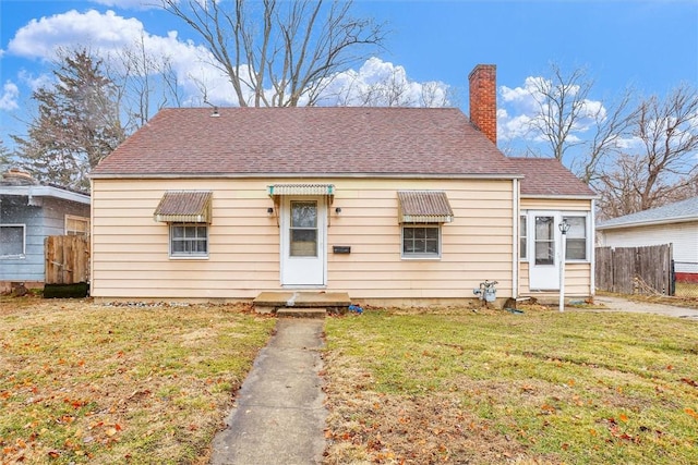 bungalow-style home featuring a front yard, roof with shingles, fence, and a chimney