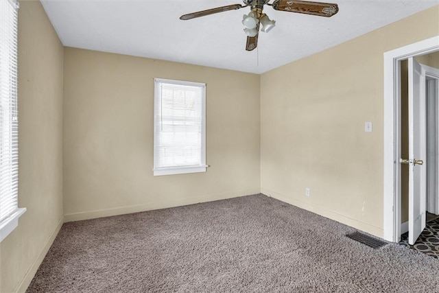 unfurnished room with carpet floors, visible vents, ceiling fan, and baseboards