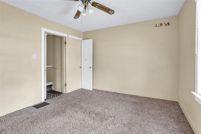 carpeted spare room featuring ceiling fan and visible vents