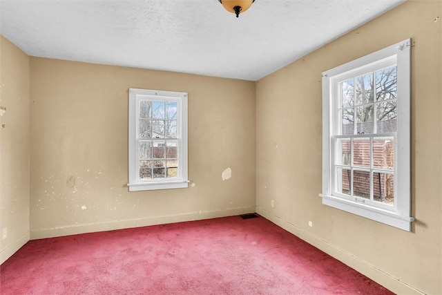 spare room featuring a textured ceiling, carpet flooring, visible vents, and baseboards