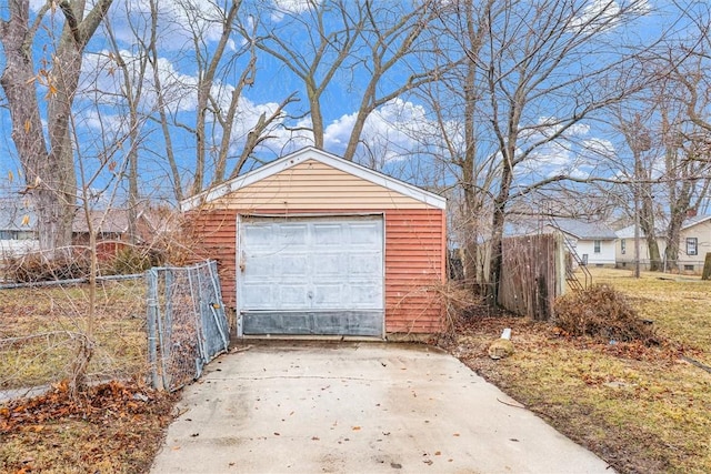 detached garage featuring driveway and fence