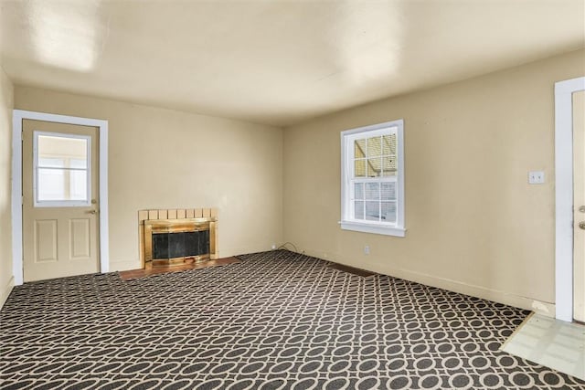 unfurnished living room with carpet floors, baseboards, and a glass covered fireplace