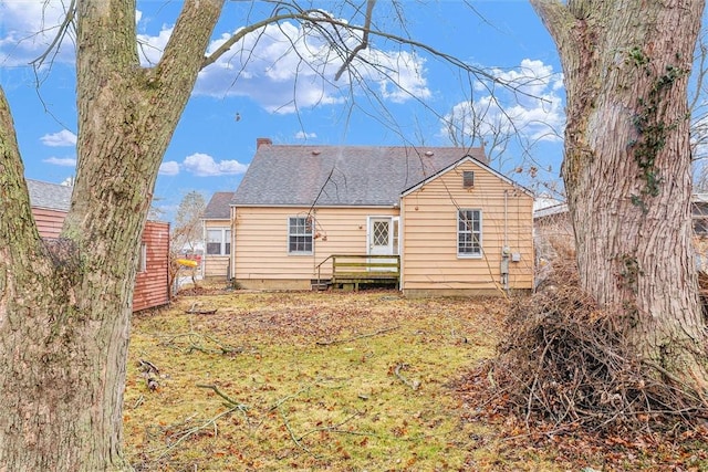 rear view of property featuring a shingled roof, fence, and a chimney