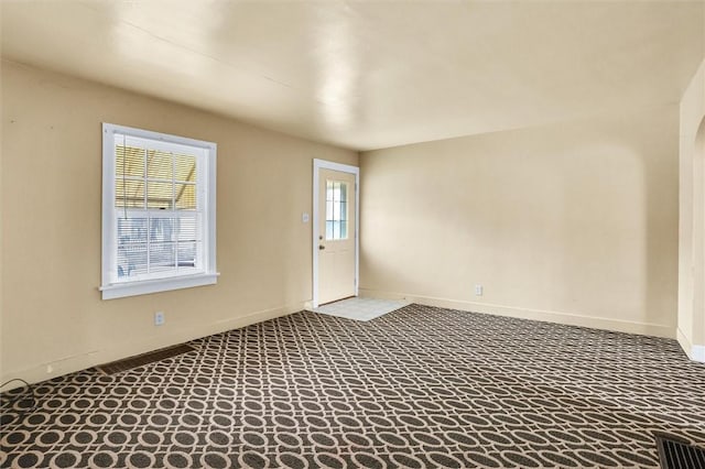 carpeted spare room with visible vents and baseboards