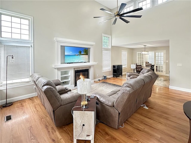 1113 Unique Ct, Mattoon, IL 61938 - living area featuring light wood-style floors, baseboards, a glass covered fireplace, ceiling fan, and a high ceiling