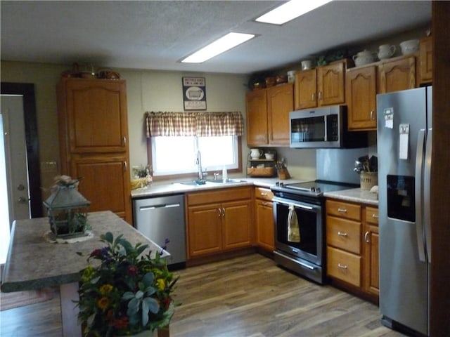 3535 Ferndale Ave, Danville, IL 61834 - kitchen featuring stainless steel appliances, a sink, brown cabinetry, wood finished floors, and light countertops