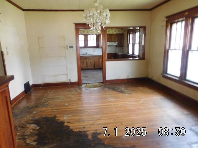 316 Plum St, Danville, IL 61832 - unfurnished dining area featuring ornamental molding, a chandelier, wood finished floors, and healthy amount of natural light