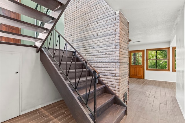 3044 Greenlake Dr, Decatur, IL 62521 - stairway featuring wood finished floors, a textured ceiling, and brick wall