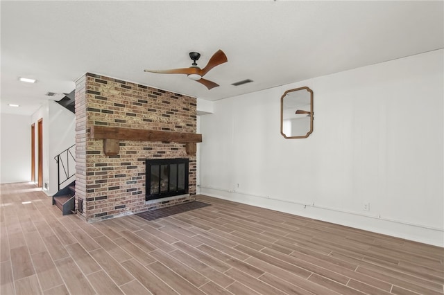 3044 Greenlake Dr, Decatur, IL 62521 - unfurnished living room with ceiling fan, wood finished floors, stairs, and a brick fireplace