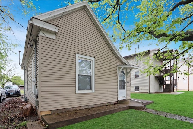 back of house with stairs and a lawn