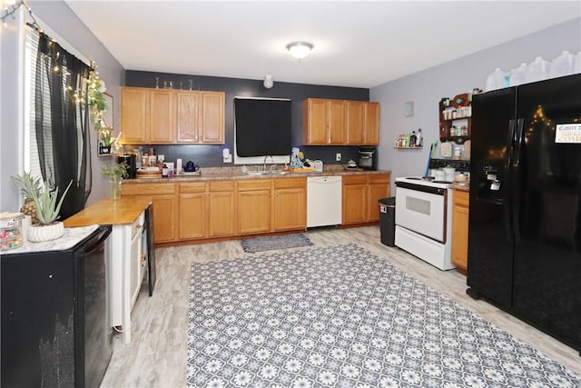 kitchen with a sink, white appliances, light countertops, light brown cabinets, and light wood-style floors