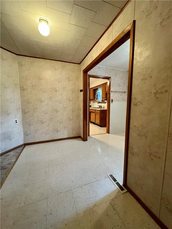 empty room with light floors, visible vents, and baseboards