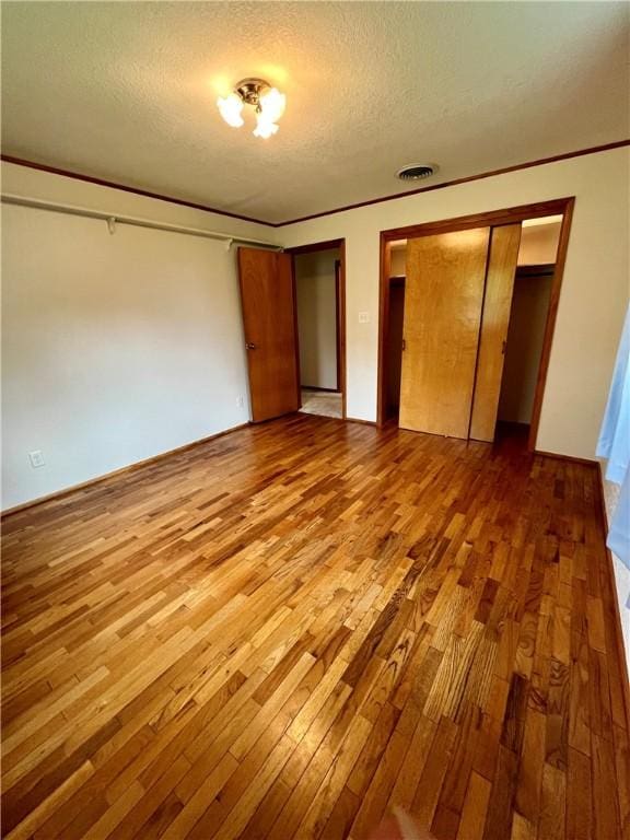 unfurnished bedroom with a textured ceiling, hardwood / wood-style floors, and visible vents