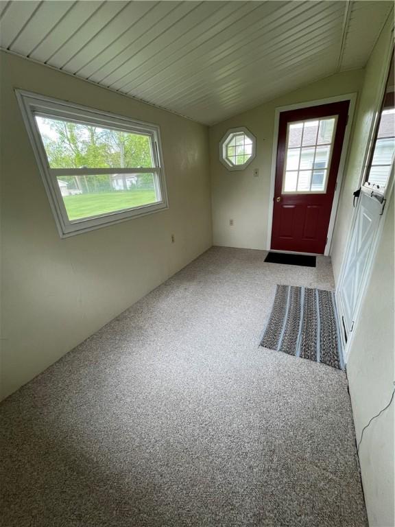 carpeted entryway featuring lofted ceiling