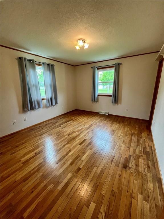empty room with ornamental molding, a wealth of natural light, and hardwood / wood-style floors