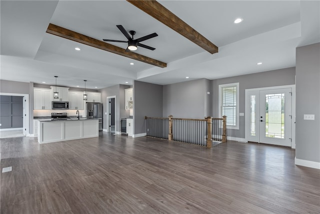 unfurnished living room with beam ceiling, ceiling fan, and dark hardwood / wood-style floors