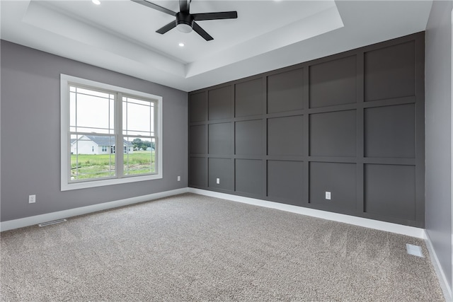 empty room featuring light colored carpet, a raised ceiling, and ceiling fan