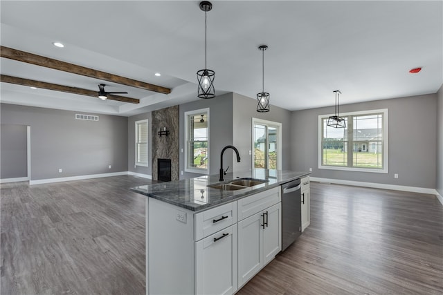 kitchen with pendant lighting, white cabinets, sink, stainless steel dishwasher, and beamed ceiling