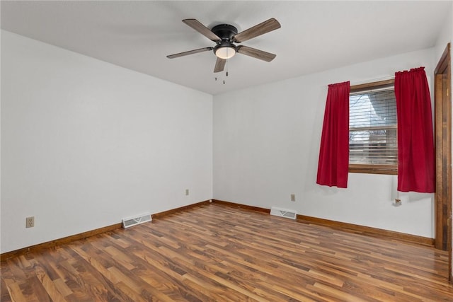 empty room with a ceiling fan, wood finished floors, visible vents, and baseboards