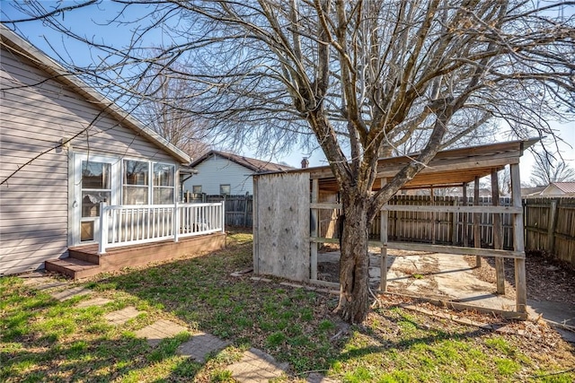 view of yard with an outbuilding, a fenced backyard, and a sunroom