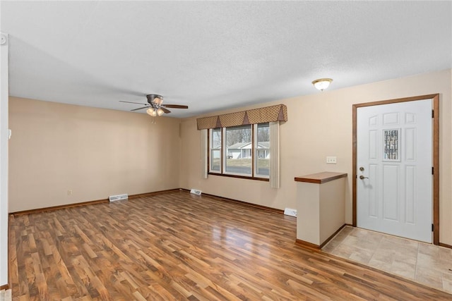 foyer featuring visible vents, baseboards, ceiling fan, wood finished floors, and a textured ceiling