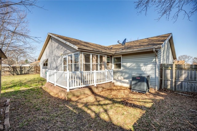 rear view of property with cooling unit, a lawn, a fenced backyard, and a sunroom