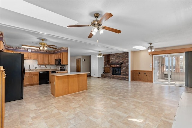 kitchen featuring a skylight, open floor plan, black appliances, and ceiling fan