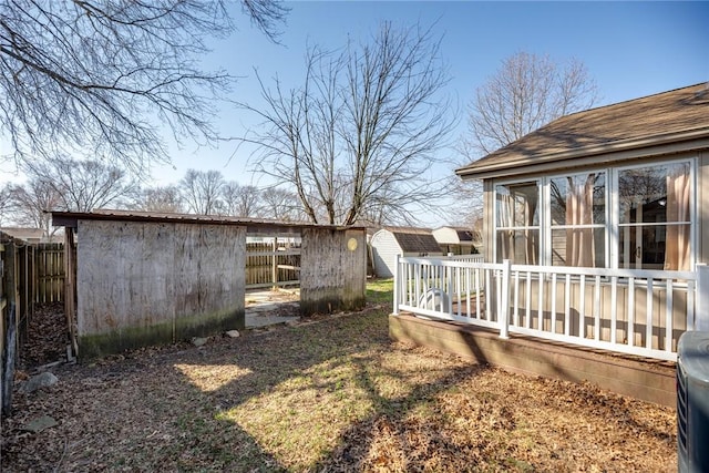 view of yard with an outbuilding, a storage shed, a sunroom, and fence