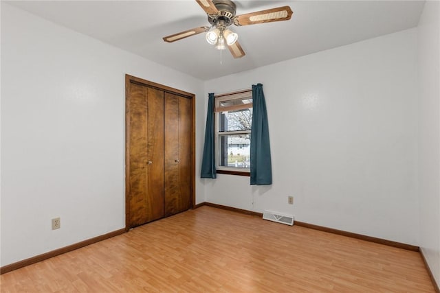 unfurnished bedroom featuring visible vents, baseboards, light wood-style floors, a closet, and a ceiling fan