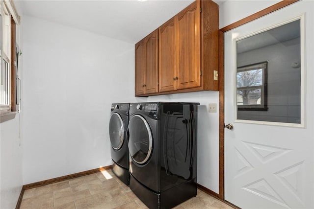 washroom featuring cabinet space, washing machine and dryer, and baseboards