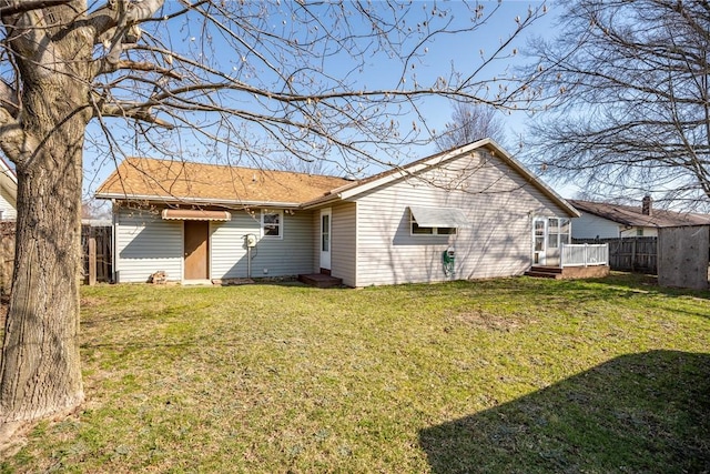 rear view of property with a yard and fence