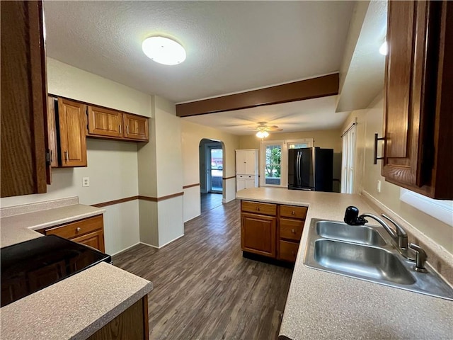 605 N 15th St, Mattoon, IL 61938 - kitchen with arched walkways, brown cabinets, a sink, freestanding refrigerator, and a peninsula
