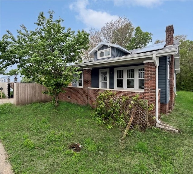 605 N 15th St, Mattoon, IL 61938 - view of side of property with fence, brick siding, a chimney, solar panels, and a yard