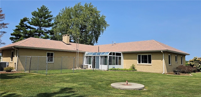 rear view of property featuring a sunroom, central AC unit, and a yard