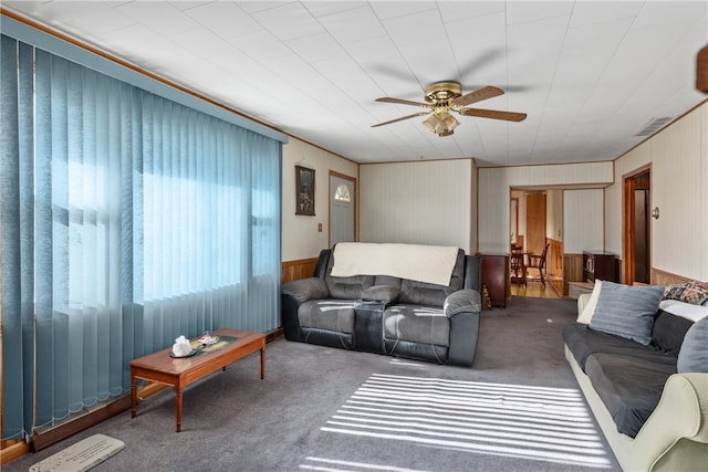 living room featuring ceiling fan, carpet floors, and wooden walls