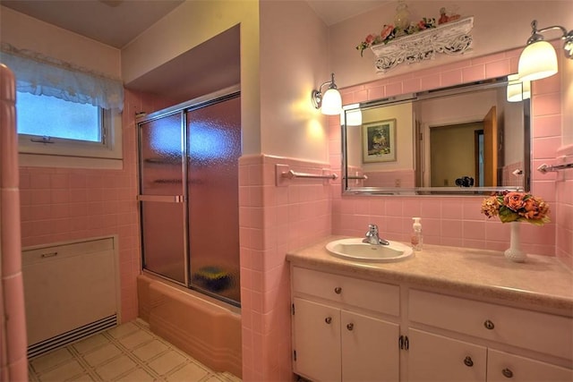 bathroom with shower / bath combination with glass door, vanity, and tile walls