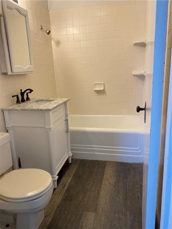 full bathroom featuring toilet, hardwood / wood-style flooring, tiled shower / bath, and vanity