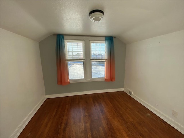 additional living space with vaulted ceiling and dark hardwood / wood-style flooring